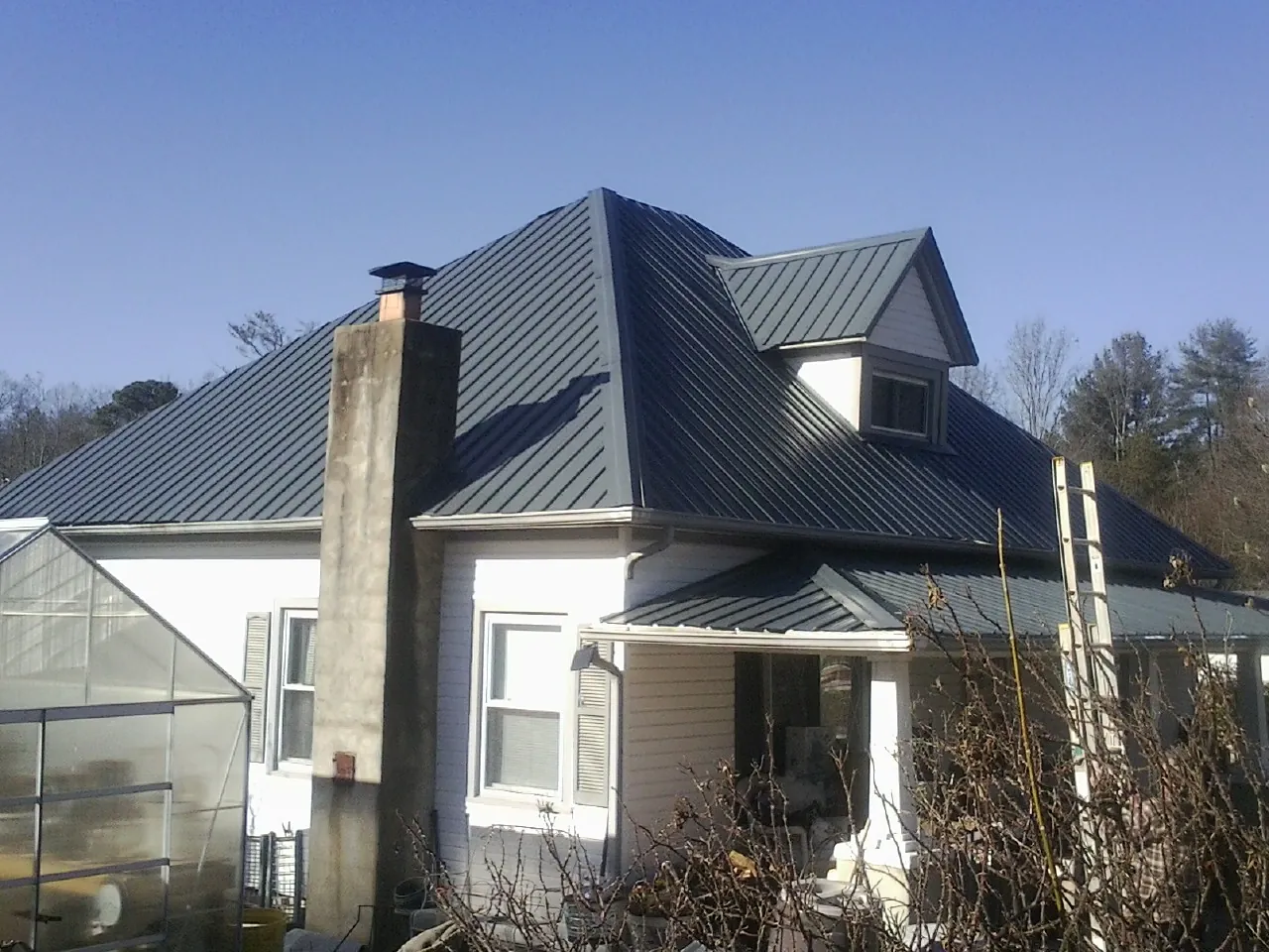 Dark blue standing seam metal roof on a white farmhouse with dormer — Slate & Tile Roof Repair by Roofing Brothers in Hilmar