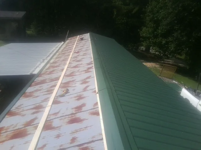 Old rusted panels beside newly installed green metal roofing — Wind Damage Roof Repair by Roofing Brothers in Hilmar