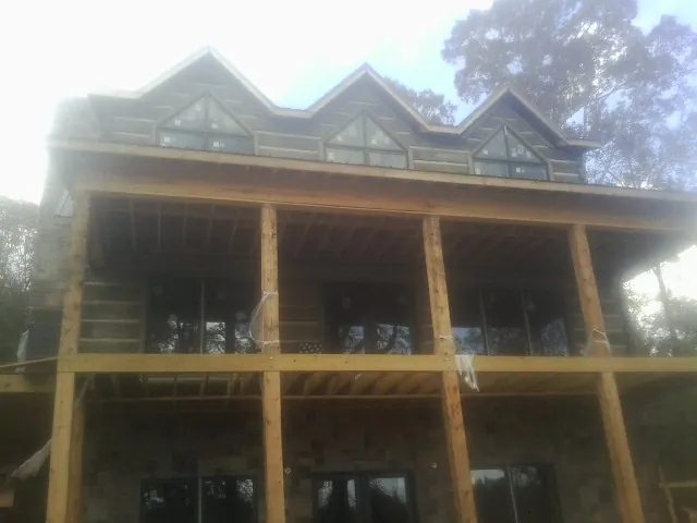 Dormers and porch framing on a large log home under construction — Roof Coating work by our crew in Hilmar