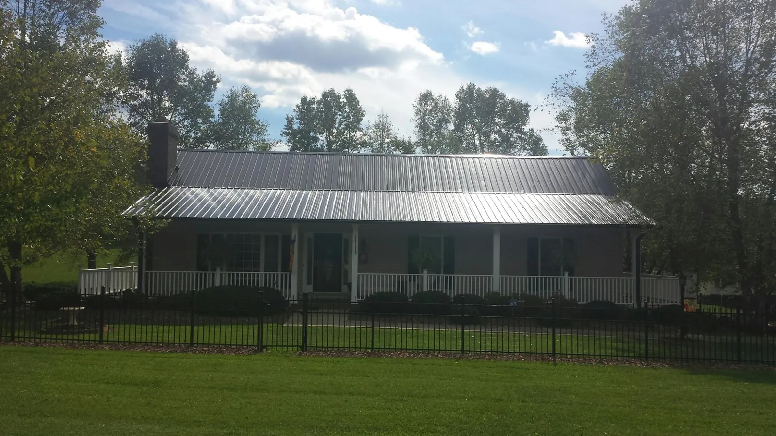 Gray metal roof on a brick ranch with a full width front porch — Gutter Guard Installation work by our crew in Hilmar